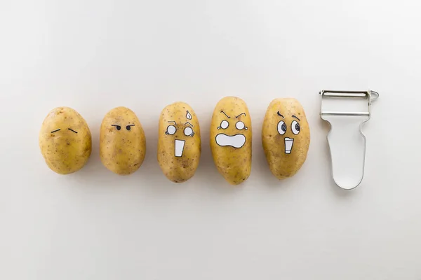 Scary face potatoes and peeler on white background — Stock Photo, Image