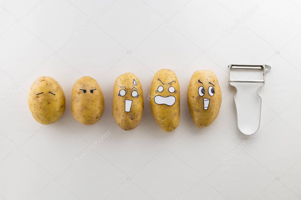 scary face potatoes and peeler on white background