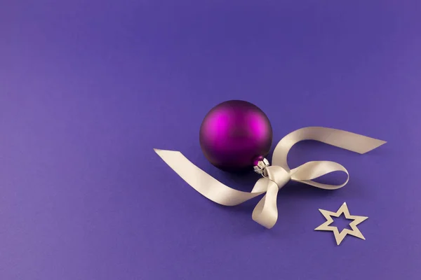 Fialová vánoční koule s hvězdami a šedou stužkou — Stock fotografie