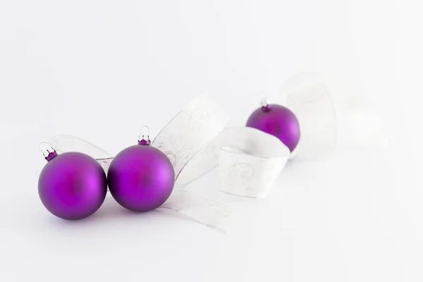 Schöne lila Weihnachtskugeln mit weißer Schleife — Stockfoto