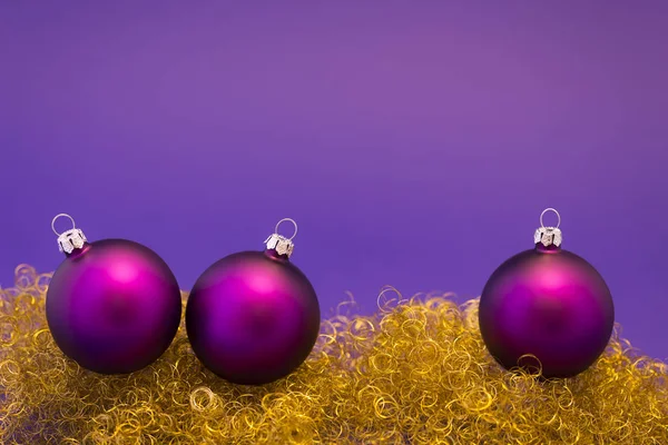 Purple christmas balls on gold glitter