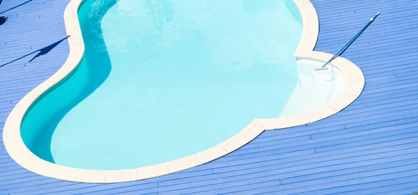 Piscina com deck azul e vassoura — Fotografia de Stock