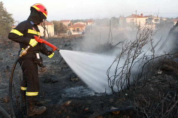 Tűzoltó eloltani a tüzet egy mezőben víz árvíz — Stock Fotó