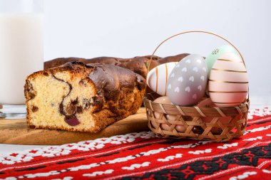 Romen sünger keki, ahşap tahtada elle dikilmiş kırmızı geleneksel havlu, Paskalya boyalı yumurta ve ev yapımı zencefilli ekmek kalbi, otantik Paskalya brunch konsepti..