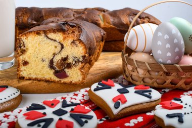 Romen sünger keki, ahşap tahtada elle dikilmiş kırmızı geleneksel havlu, Paskalya boyalı yumurta ve ev yapımı zencefilli ekmek kalbi, otantik Paskalya brunch konsepti..