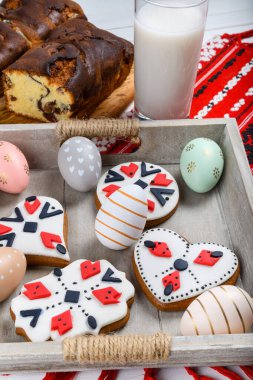 Romen sünger keki, ahşap tahtada elle dikilmiş kırmızı geleneksel havlu, Paskalya boyalı yumurta ve ev yapımı zencefilli ekmek kalbi, otantik Paskalya brunch konsepti..