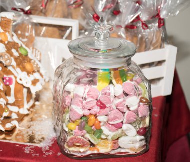 Kırmızı kadifede el yapımı zencefilli Noel kurabiyesi evi. Avrupa Noel gelenekleri. Noel tatili tatlıları ve hediyeler şekerleme masasında sergileniyor. Ev yapımı geleneksel tatlı.