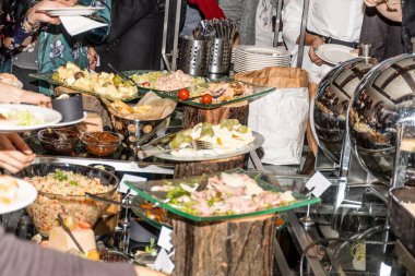 Brunch büfesi sırasında masadaki insanlar elleriyle tabağa yemek koyarlar. Yemek Büfesi Yemek Yeme Partisi Paylaşım Konsepti. Birçok uluslararası yemeğin restoranda sergilenmesi, çeşitli yiyecekler