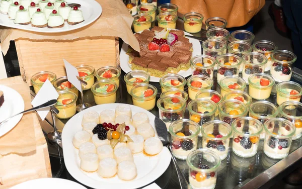 Dessert buffet or candy bar during catering event. Many different sweets closeup: cookies, pastry, bakery, tart, cake, muffins, cups, lemon, vanilla, white and dark chocolate, fruits and whipped cream
