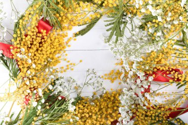 Çiçek arka plan, bahar kavramı, beyaz tahta, kırmızı kurdele, sarı Mimosa gibi bahar çiçekleri. Metin için boşluk, ortadaki boşluğu kopyala