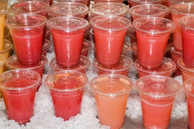 Pek çok kırmızı sarı meyve suyu, kokteyl bardakları, plastik içecekler ve yaz mevsiminde dükkan tezgahında örtüler.