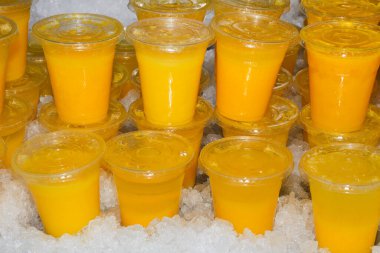 Pek çok kırmızı sarı meyve suyu, kokteyl bardakları, plastik içecekler ve yaz mevsiminde dükkan tezgahında örtüler.