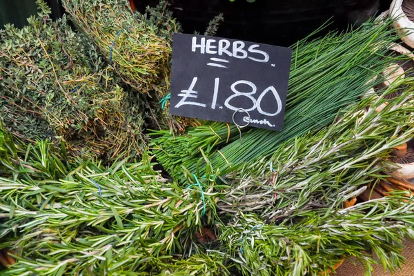 Green herbs for sale. Local produce for sale displayed at the market. Borough farmer's market in London. Organic and bio fresh healthy eating concept. Veggies, vegetables, herbs and spices, price tags