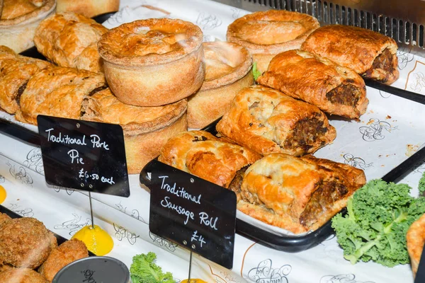 Traditional British puff pastry items, displayed in a bakery or pastry shop. Sausage rolls