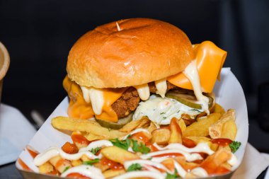 Fast food festivalinde yenmeye hazır taze erimiş hamburger. Açık hava yemek organizasyonu, brunch ya da fast food ile akşam yemeği partisi. Erimiş peynir ve altın çörek. İştah açıcı ev yapımı hamburger.