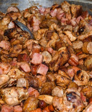 Sağlıksız, yağlı, yağlı, et dilimleri karışımı, fast food festivalinde büyük bir tencerede kızarma. Geleneksel Romanya yemeği olan 