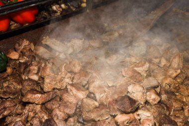 Sağlıksız, yağlı, yağlı, et dilimleri karışımı, fast food festivalinde büyük bir tencerede kızarma. Geleneksel Romanya yemeği olan 