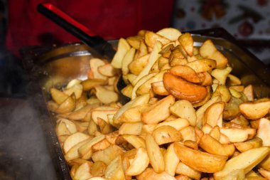 Peynirli ve otlu fırında patates ve siyah arka planda domates sosu. Ev yapımı vejetaryen sebze, vejetaryen patates, abur cubur. Kızarmış patates, otlu ve tuzlu.