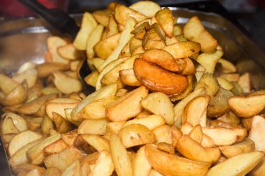 Peynirli ve otlu fırında patates ve siyah arka planda domates sosu. Ev yapımı vejetaryen sebze, vejetaryen patates, abur cubur. Kızarmış patates, otlu ve tuzlu.