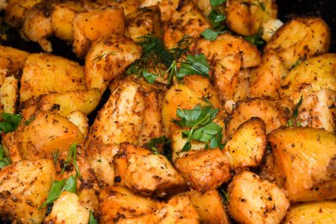 Peynirli ve otlu fırında patates ve siyah arka planda domates sosu. Ev yapımı vejetaryen sebze, vejetaryen patates, abur cubur. Kızarmış patates, otlu ve tuzlu.