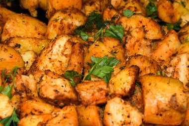 Peynirli ve otlu fırında patates ve siyah arka planda domates sosu. Ev yapımı vejetaryen sebze, vejetaryen patates, abur cubur. Kızarmış patates, otlu ve tuzlu.