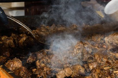 Sağlıksız, yağlı, yağlı, et dilimleri karışımı, fast food festivalinde büyük bir tencerede kızarma. Geleneksel Romanya yemeği olan 