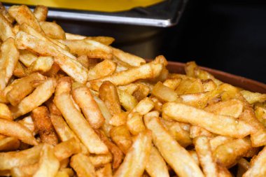 Peynirli ve otlu fırında patates ve siyah arka planda domates sosu. Ev yapımı vejetaryen sebze, vejetaryen patates, abur cubur. Kızarmış patates, otlu ve tuzlu.