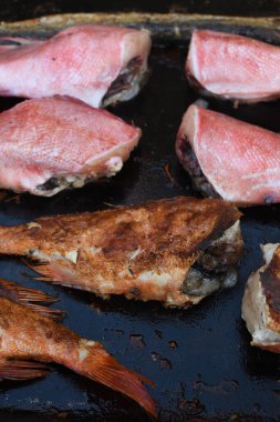 Izgara tahtasında taze çiğ balık, deniz ürünleri festivali sırasında, sokak yemekleri pazarında. Kızıl deniz levreği, alabalık, kılıç balığı, çeşitli deniz ürünleri çeşitleri yakın çekim, üst manzara. Balığın tamamı ızgarada pişmemiş.