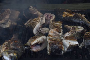 Tezgahın üstünde taze ızgara balık, deniz ürünleri festivali sırasında, sokak yemekleri pazarında. Kızıl deniz levreği, alabalık, kılıç balığı, kızarmış altın kalamar, çeşitli deniz ürünleri çeşitleri yakın çekim, üst manzara..