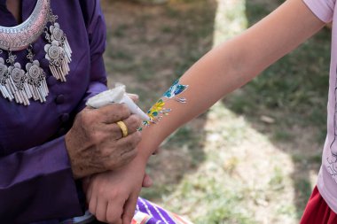 Çocuk elinin üzerinde geleneksel Tayland giysi resmi olan bir kadın. Vücut sanatı. Ressam elinde boya fırçası tutuyor ve işini yapıyor..