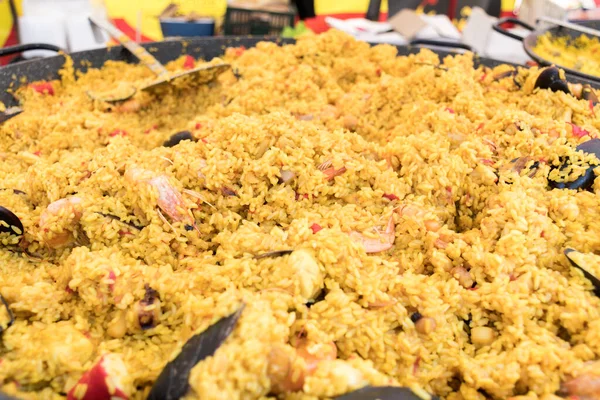 Seafood paella cooked in a large pan wok, street food festival. Mexican fiesta national day dish specialty. Live cooking station. Fresh Food Buffet Brunch Catering Dining Eating Party Sharing Concept