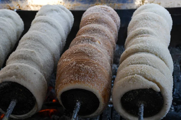 Kurtos kalacs or chimney cakes, preparing cooking on charcoal grill, street food traditional Hungarian, during food festival. Kurtos Kalacs traditional hungarian cake, baked with sugar, honey and nuts
