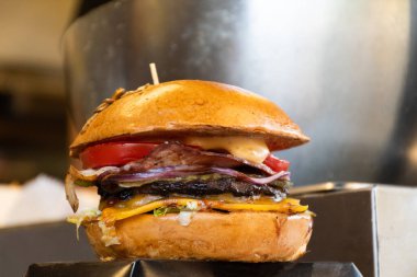 Fast food festivalinde yenmeye hazır taze erimiş hamburger. Açık hava yemek organizasyonu, brunch ya da fast food ile akşam yemeği partisi. Erimiş peynir ve altın çörek. İştah açıcı ev yapımı hamburger.