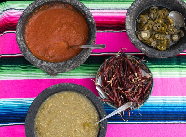 Spiced red tomato salsa and spiced green salsa for seasoning traditional Mexican food at a street food market, selective focus. Green jalapeno spicy dipping sauce and red peppers tomato spicy chili