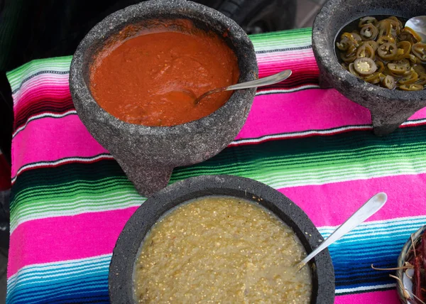 Spiced red tomato salsa and spiced green salsa for seasoning traditional Mexican food at a street food market, selective focus. Green jalapeno spicy dipping sauce and red peppers tomato spicy chili
