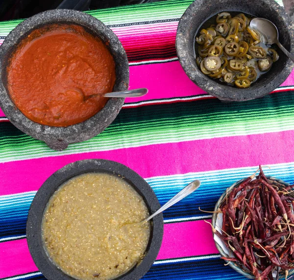 Spiced red tomato salsa and spiced green salsa for seasoning traditional Mexican food at a street food market, selective focus. Green jalapeno spicy dipping sauce and red peppers tomato spicy chili