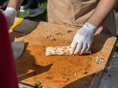 Lahmacun adı verilen geleneksel Türk pizzası, et, soğan ve maydanozla bir sokak yiyecek pazarında ahşap bir masada sergileniyor.