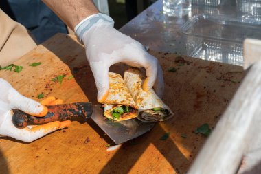 Lahmacun adı verilen geleneksel Türk pizzası, et, soğan ve maydanozla bir sokak yiyecek pazarında ahşap bir masada sergileniyor.
