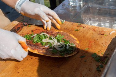 Lahmacun adı verilen geleneksel Türk pizzası, et, soğan ve maydanozla bir sokak yiyecek pazarında ahşap bir masada sergileniyor.