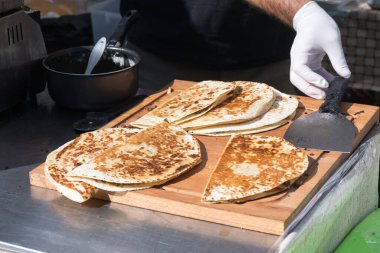 Lahmacun adı verilen geleneksel Türk pizzası, et, soğan ve maydanozla bir sokak yiyecek pazarında ahşap bir masada sergileniyor.