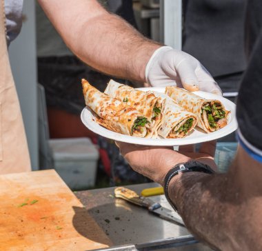 Lahmacun adı verilen geleneksel Türk pizzası, et, soğan ve maydanozla bir sokak yiyecek pazarında ahşap bir masada sergileniyor.