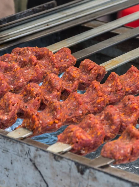 Adana kebab (ground lamb minced meat on skewer on grill over charcoal).Chef preparing traditional authentic Turkish shaworma. Middle eastern cuisine. Handmade specialty street food market with spices