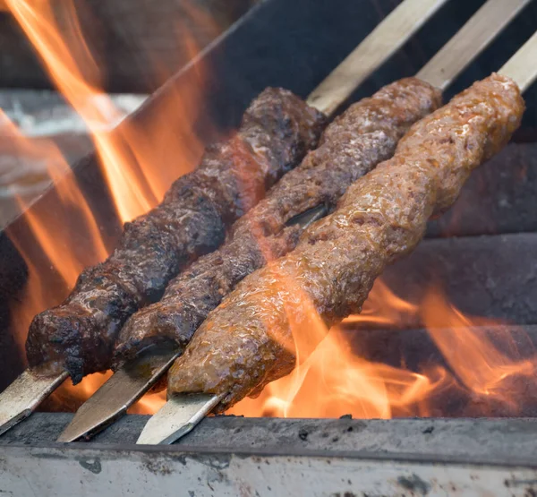 Adana kebab (ground lamb minced meat on skewer on grill over charcoal).Chef preparing traditional authentic Turkish shaworma. Middle eastern cuisine. Handmade specialty street food market with spices