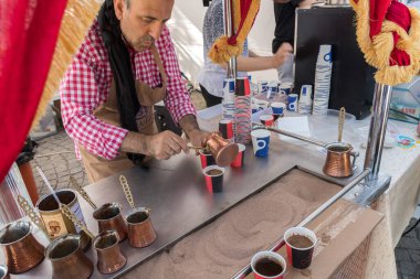 Bükreş, Romanya, 21 Eylül 2019: Yemek festivali sırasında sokakta sıcak kum hazırlanmasıyla yapılan Türk kahvesi. Ayrıca kahve tarifi. Orijinal geleneksel duruş