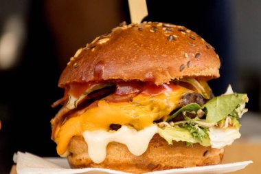 Fast food festivalinde yenmeye hazır taze erimiş hamburger. Açık hava yemek organizasyonu, brunch ya da fast food ile akşam yemeği partisi. Erimiş peynir ve altın çörek. İştah açıcı ev yapımı hamburger.