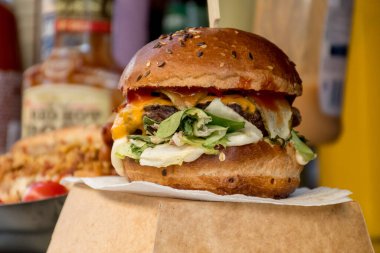 Fast food festivalinde yenmeye hazır taze erimiş hamburger. Açık hava yemek organizasyonu, brunch ya da fast food ile akşam yemeği partisi. Erimiş peynir ve altın çörek. İştah açıcı ev yapımı hamburger.