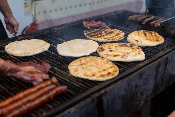 Chef preparing meat on the grill, during outdoor outside food festival, food truck, brunch or catering event. Pork steaks, chicken breast, sausages, high protein unhealthy or fat pieces of meat chops