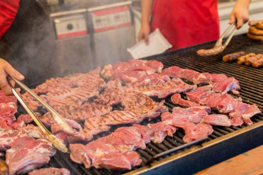 Şef ızgarada et hazırlıyor, dışarıda yemek festivali, yemek kamyonu, brunch ya da catering etkinliği sırasında. Domuz bifteği, tavuk göğsü, sosis, yüksek protein, sağlıksız ve şişman et parçaları.