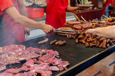Şef ızgarada et hazırlıyor, dışarıda yemek festivali, yemek kamyonu, brunch ya da catering etkinliği sırasında. Domuz bifteği, tavuk göğsü, sosis, yüksek protein, sağlıksız ve şişman et parçaları.