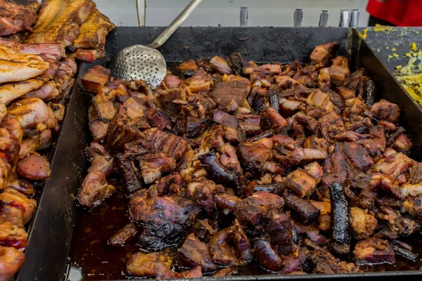 Chef preparing meat on the grill, during outdoor outside food festival, food truck, brunch or catering event. Pork steaks, chicken breast, sausages, high protein unhealthy or fat pieces of meat chops